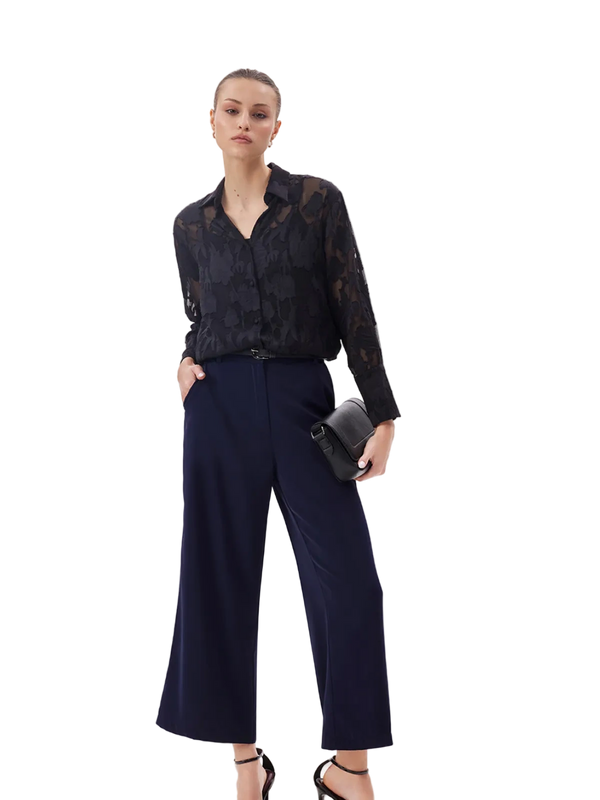 Woman wearing a black lace top and dark blue pants on a white background