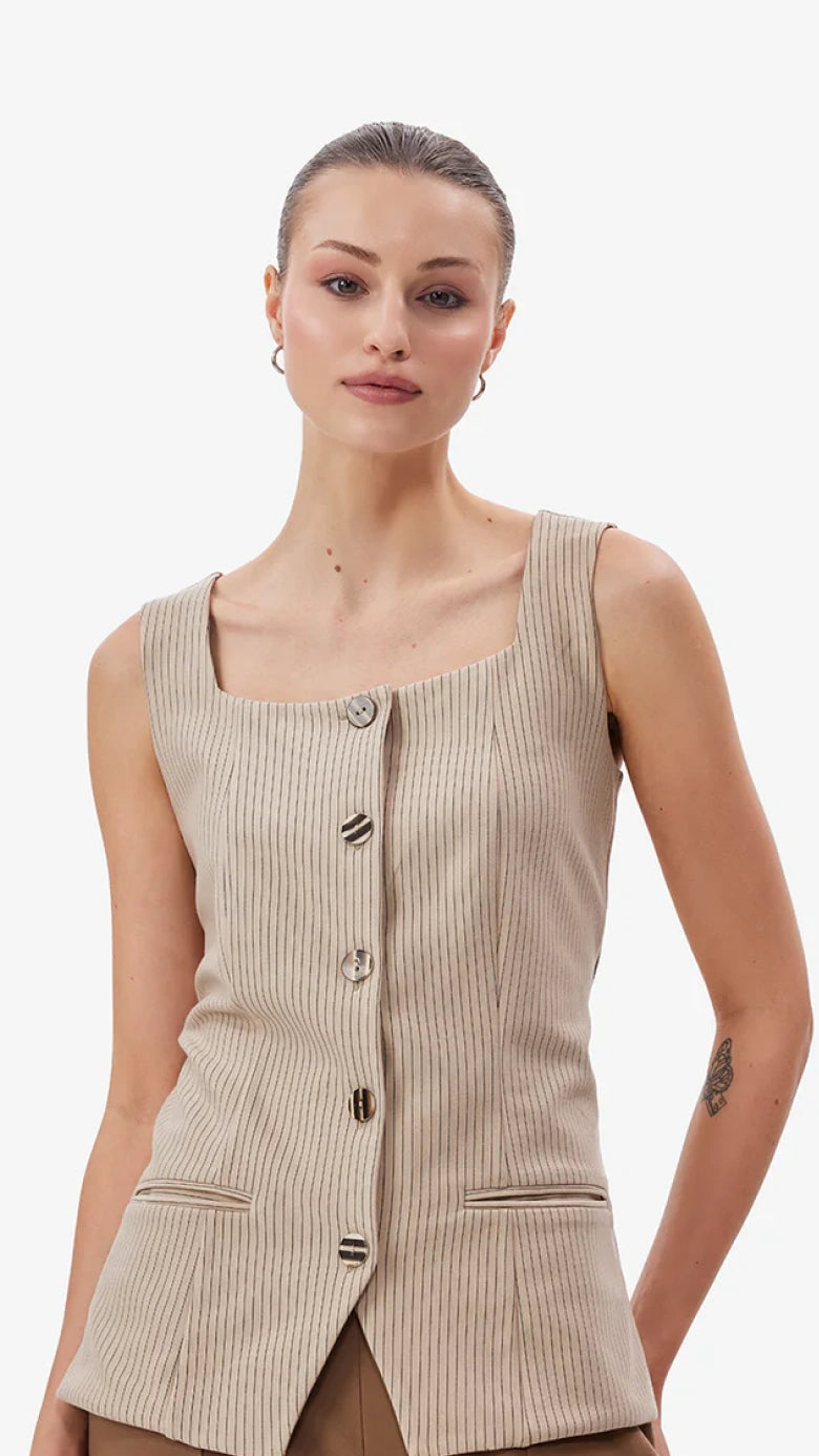 Woman wearing a beige ribbed tank top with buttons on a white background